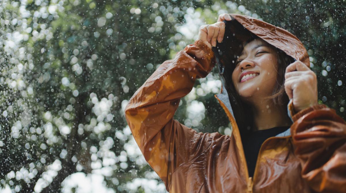 A woman wearing an orange rain jacket in the rain.